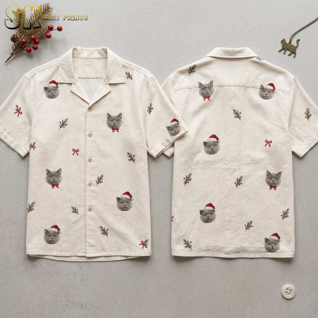 Both sides of a cream mens christmas aloha shirt laid flat, showing repeated gray cat faces in Santa hats and bow ties alongside holly sprigs and red bows on the front and back panels.