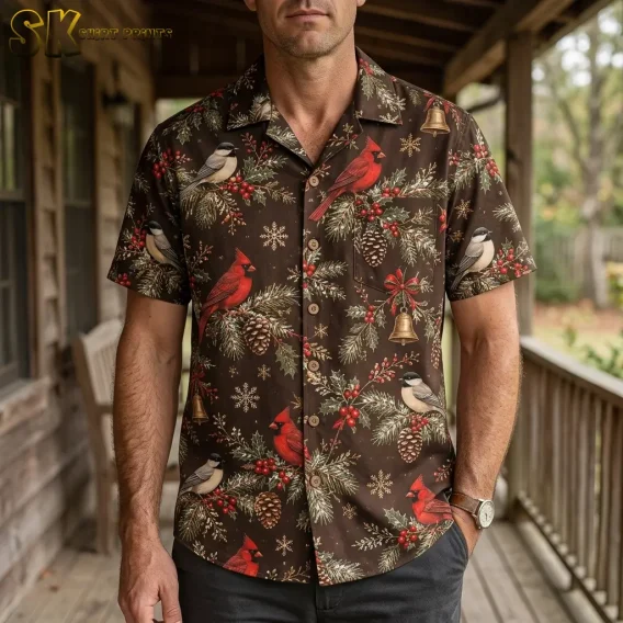 A man wearing a mens christmas hawaiian shirt stands on a wooden porch, with red cardinals and golden bells clearly visible across the chest and front placket.