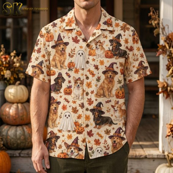 Man wearing a cream short-sleeve button-up shirt printed with costumed dogs, jack-o'-lanterns, and autumn leaves in a dense all-over pattern.