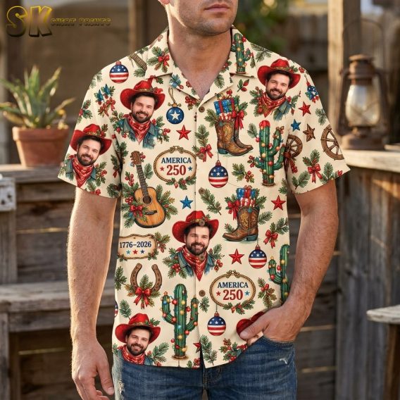 A man wearing the cream all-over printed shirt stands outdoors with rustic wooden structures behind him, the repeated cowboy portrait and America 250 plaques clearly visible across the chest.