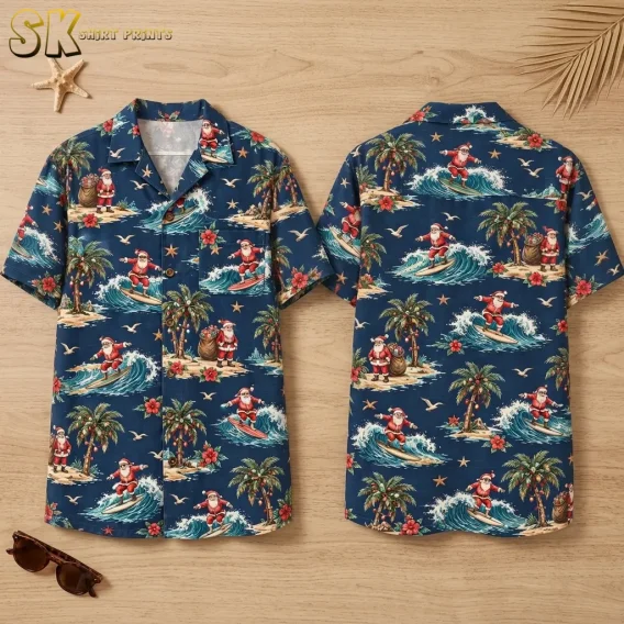 A navy surfing Santa Hawaiian shirt is laid out in front and back views on a wood surface beside sunglasses and a starfish.