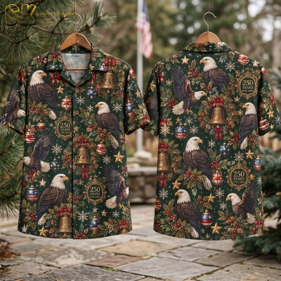 Flat lay of the dark green short-sleeve button-up shirt showing both the front and back panels, with the full repeating pattern of bald eagles, Christmas bells, baubles, snowflakes, and 250 YEARS 1776-2026 circular badges clearly visible.