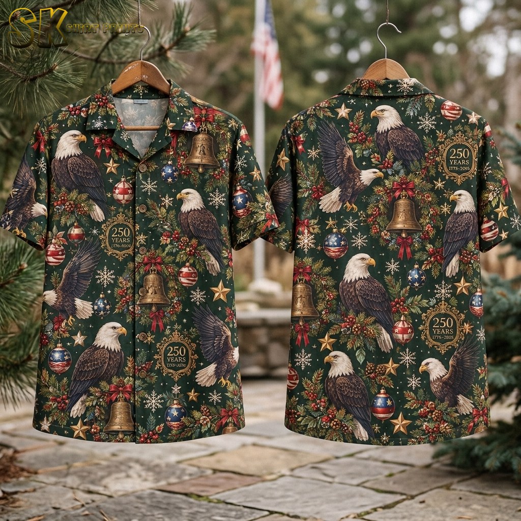 Flat lay of the dark green short-sleeve button-up shirt showing both the front and back panels, with the full repeating pattern of bald eagles, Christmas bells, baubles, snowflakes, and 250 YEARS 1776-2026 circular badges clearly visible.