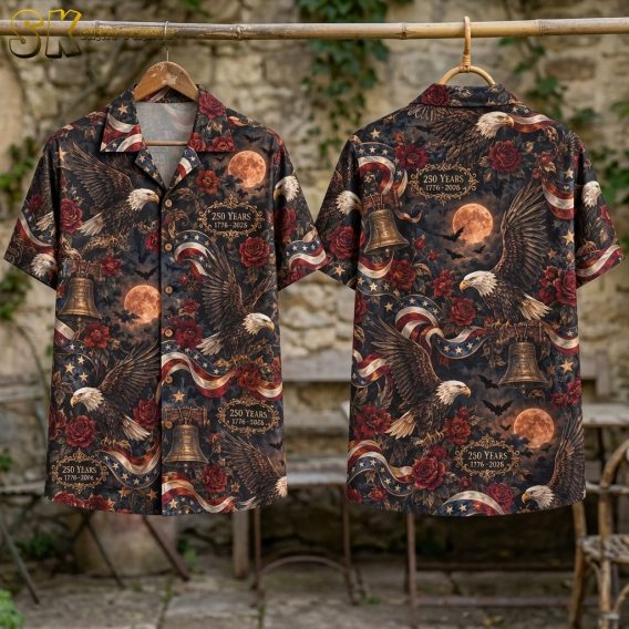 Flat-lay front and back views of the short-sleeve button-up shirt on a surface, clearly showing the camp collar, button placket, and the full all-over pattern with eagles, Liberty Bells, full moons, bats, and gold-framed anniversary text.