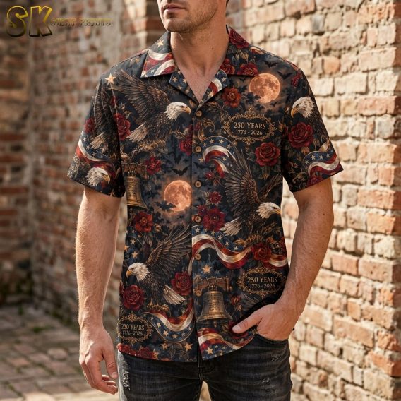 A man wearing the dark-toned short-sleeve button-up shirt, showing how the dense all-over pattern of eagles, flags, and bats looks when worn.