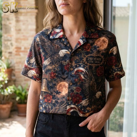 A close-up view on a woman showing the shirt's intricate artwork, including a realistically illustrated bald eagle, flying bats, red roses, and a gold ornate frame with commemorative text.