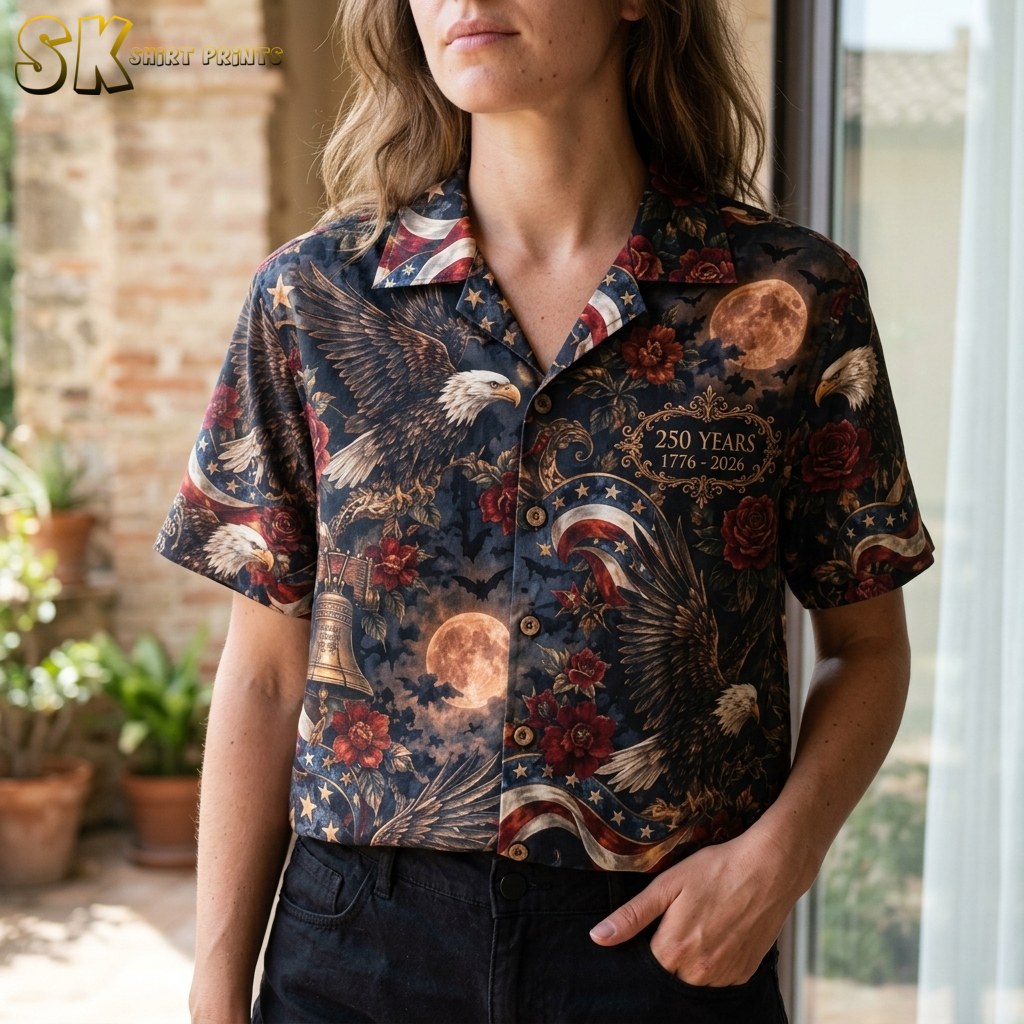 A close-up view on a woman showing the shirt's intricate artwork, including a realistically illustrated bald eagle, flying bats, red roses, and a gold ornate frame with commemorative text.