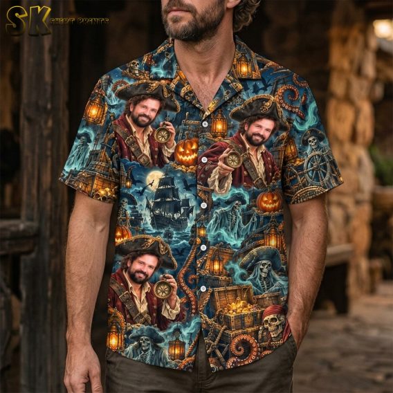 A man wearing the dark blue short-sleeve button-up shirt featuring the all-over pirate and Halloween print with glowing lanterns, pumpkins, and ghostly pirate figures.