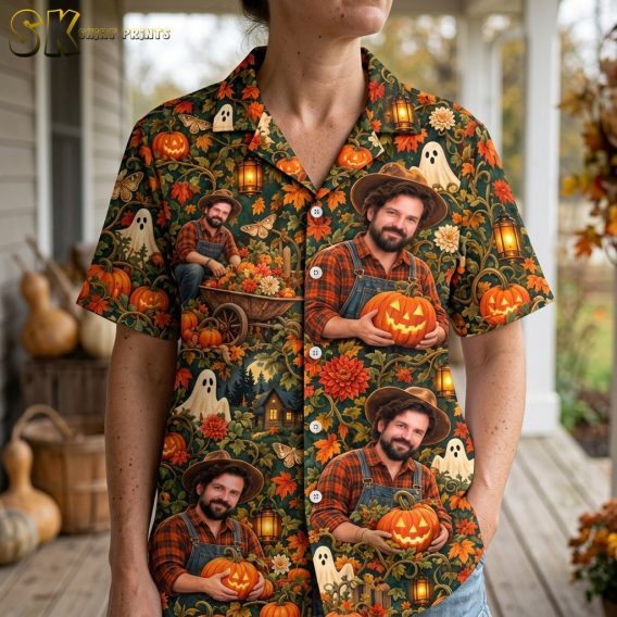 A close-up view on a woman wearing the dark green spooky hawaiian shirt, bringing out details such as the cartoonish white ghosts, orange pumpkins, moths, and chrysanthemum flowers in the print.