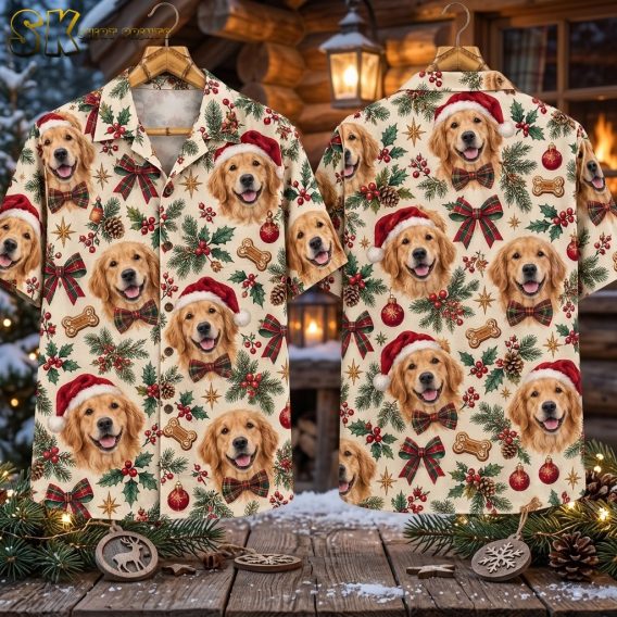 The front and back of the santa hawaiian shirt are laid flat side by side on a rustic wooden surface surrounded by pine cones, fir branches, and Christmas ornaments, with a glowing fireplace visible behind.