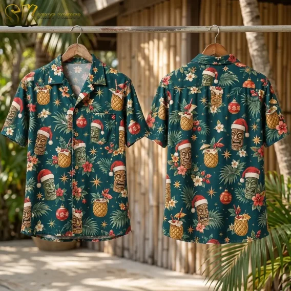 Front and back of a santa hawaiian shirt hang side by side on wooden hangers against a bamboo wall, displaying the full teal repeat pattern of tiki faces, pineapple cocktails, and Christmas ornaments.