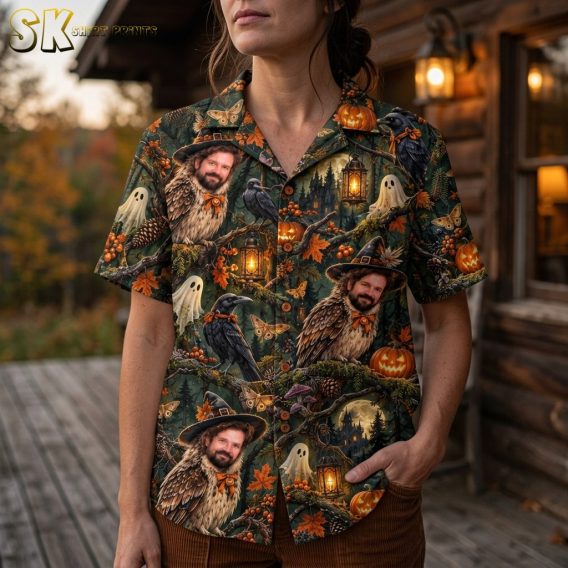 Close-up view of a woman wearing the horror Hawaiian shirt, highlighting the detailed illustration of owls with a man's face, glowing lanterns with lit candles, black crows with orange bows, and small ghost figures against the dark green background.