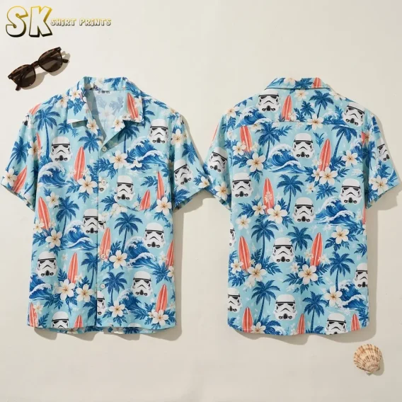 Front and back of a light blue stormtrooper Hawaiian shirt laid flat beside sunglasses and a seashell.