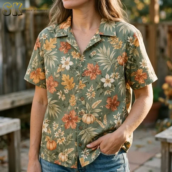 A woman wears an olive green autumn-print shirt with jeans, with a close-up showing its collar, brown buttons, and pumpkin illustrations.