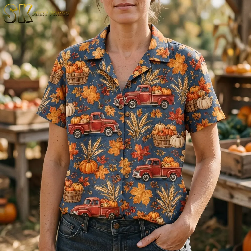 A woman wears a blue-gray harvest shirt tucked into jeans, with pumpkin baskets and red trucks visible across the front.