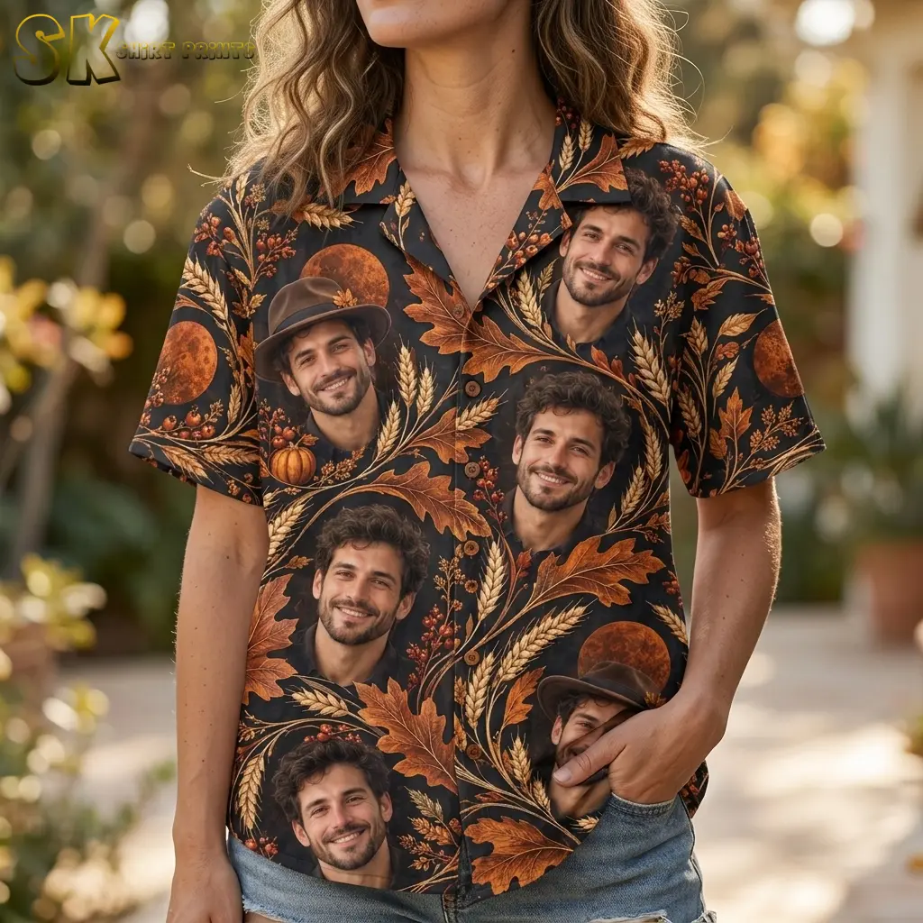 A woman wears a black short-sleeve shirt with smiling portrait faces, wheat, and orange leaves, paired with denim shorts.