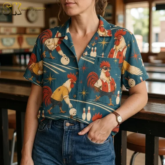 A woman wears a teal bowling rooster shirt tucked into blue jeans, with the collar, buttons, and chest pocket shown close up.