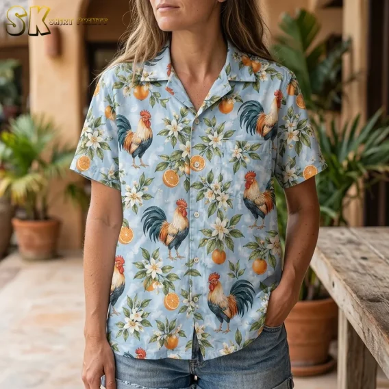 A woman wears a light blue rooster-print shirt with denim shorts, showing the collar, buttons, and left chest pocket.