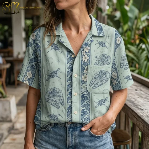 A woman wears a seafoam green Star Wars Hawaiian button up shirt with jeans, showing the open collar and spacecraft-print chest pocket.
