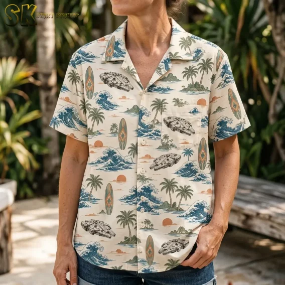 A woman wears a cream tropical button-up shirt with a spacecraft illustration on the chest pocket and blue waves across the front.