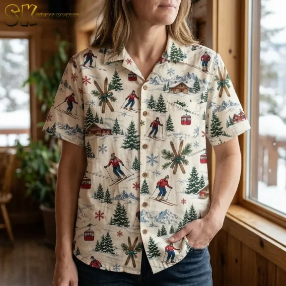 A woman wearing the hawaiian christmas shirt stands near a large window inside a wood-paneled cabin, with snowy trees outside and the gondola and skier motifs prominent across the front.