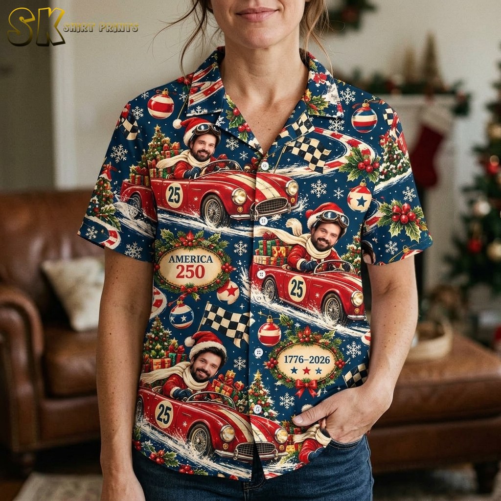 A woman wearing the shirt indoors near a decorated Christmas tree, with the camera close enough to clearly read the 'America 250' oval plaque and show the detail of the Santa-hatted race car driver illustration.