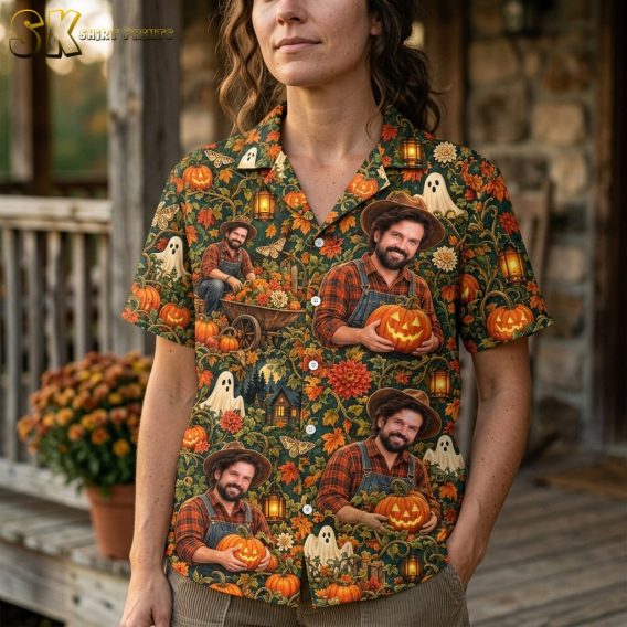 A woman wearing the pumpkin hawaiian shirt stands on a porch, with the close-up framing revealing the layered motifs—grinning jack-o'-lanterns, white cartoon ghosts, golden butterflies, and a wheelbarrow scene—woven into the green vine-covered background.