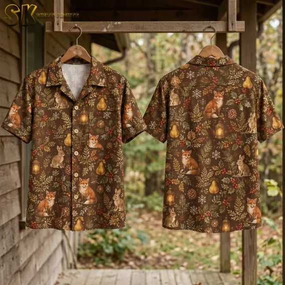 Two xmas hawaiian shirts hang side by side on wooden hangers against an outdoor wooden wall, showing the front with its chest pocket and the back with a prominent sitting fox surrounded by snowflakes and holly.